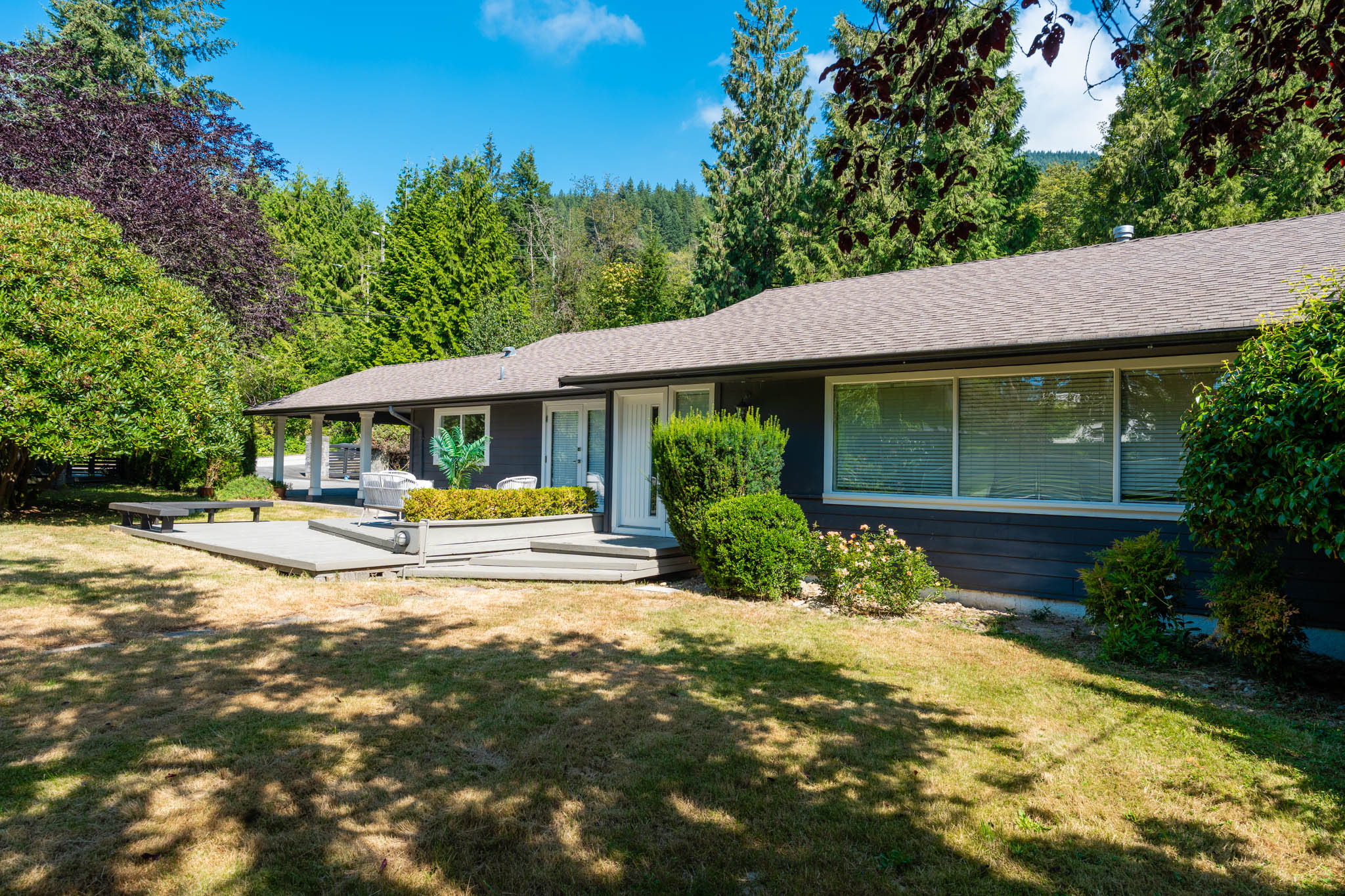 West Coast home exterior surrounded by mature trees and landscaped greenery